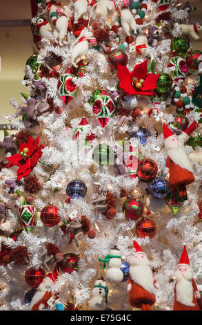 Colourful seasonal Xmas decorations and baubles on a white Xmas tree in a department store festive Christmas display in New York Stock Photo