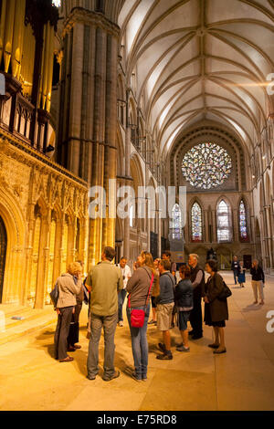 Group of tourists on a guided tour, and the Bishops Eye stained glass window; Lincoln Cathedral interior, Lincoln UK Stock Photo