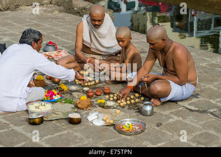 Two men, a boy and a pandit, priest, are performing Dashkriya or Asthi ...
