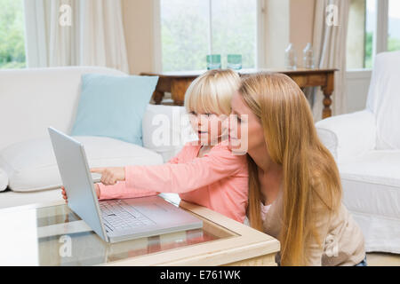 Cute daughter and mother using laptop on coffee table Stock Photo