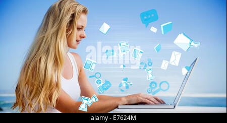 Composite image of pretty blonde using her laptop at the beach Stock Photo