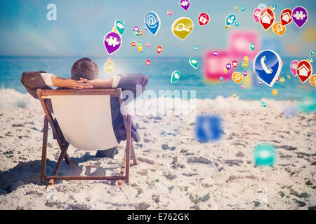 Composite image of young businessman relaxing on his sun lounger Stock Photo