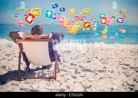 Composite image of young businessman relaxing on his sun lounger Stock Photo