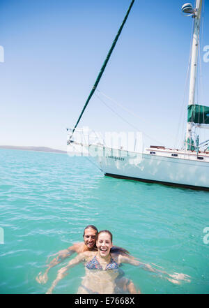 Couple swimming in water near boat Stock Photo