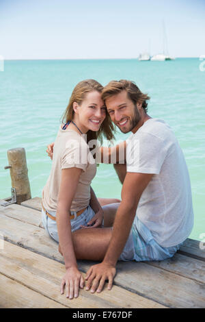 Couple sitting on edge of wooden dock together Stock Photo