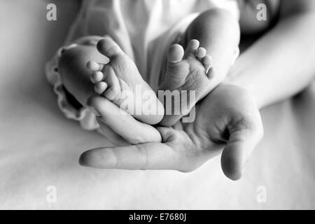 Parent hand hold baby girl legs Stock Photo