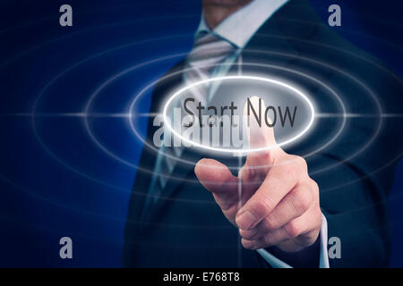Businessman pressing a Start Now concept button. Stock Photo