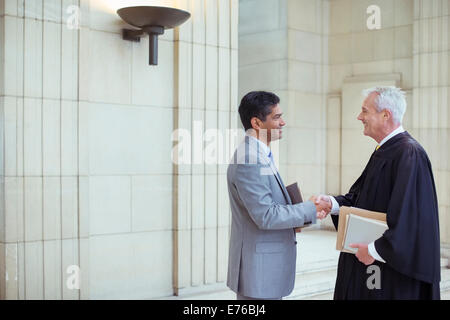 Judge and lawyer shaking hands in courthouse Stock Photo