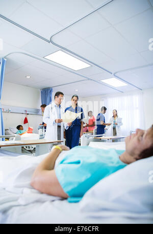 Doctor and nurse reading medical chart in hospital room Stock Photo