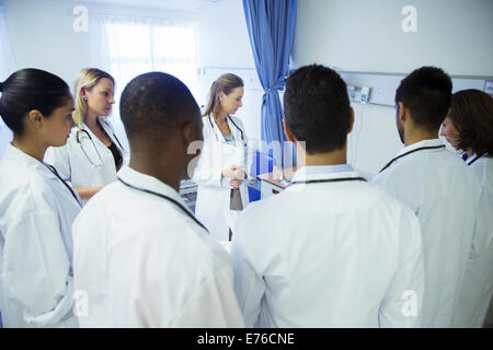 Doctor and residents examining patient in hospital room Stock Photo