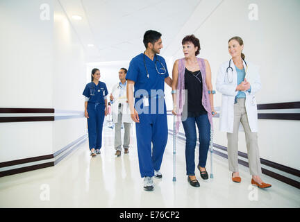 Doctor and nurse walking patient down hospital hallway Stock Photo