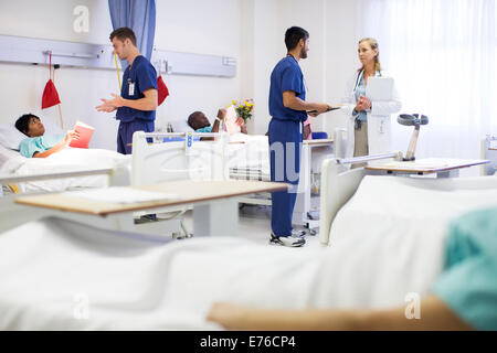 Doctor, nurses, and patients in hospital room Stock Photo