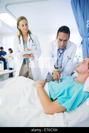 Doctors examining patient in hospital room Stock Photo