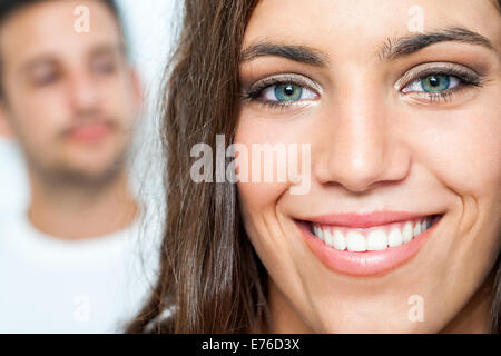 Close up Facial portrait of attractive girl with toothy smile and boy in background. Stock Photo