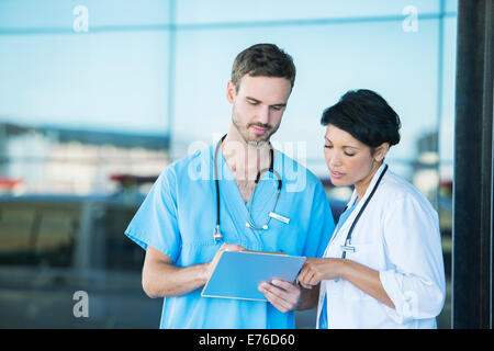 Doctor and nurse reading medical chart outdoors Stock Photo