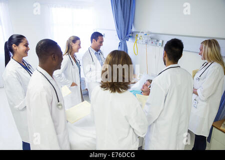 Doctor and residents examining patient in hospital room Stock Photo