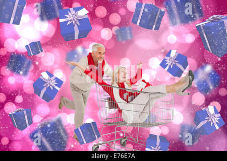 Composite image of happy festive couple messing in trolley Stock Photo