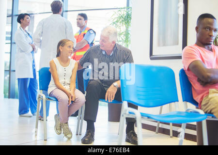 Man and granddaughter sitting in hospital waiting room Stock Photo
