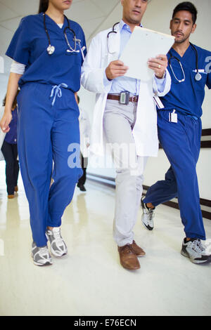 Doctor and nurses reading medical chart in hospital hallway Stock Photo