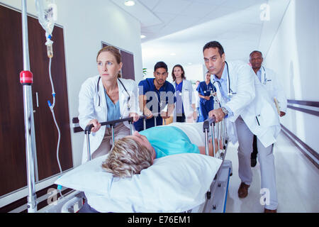 Doctors and nurses wheeling patient down hospital hallway Stock Photo