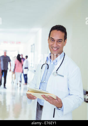 Doctor reading medical chart in hospital hallway Stock Photo