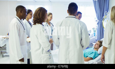 Doctor and residents examining patient in hospital room Stock Photo