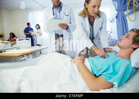 Doctors examining patient in hospital room Stock Photo