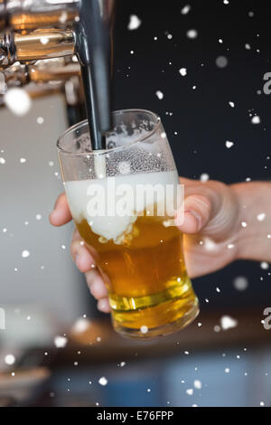 Composite image of hand holding glass filling beer Stock Photo