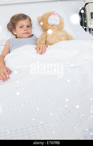 Composite image of girl with teddy bear lying in hospital bed Stock Photo