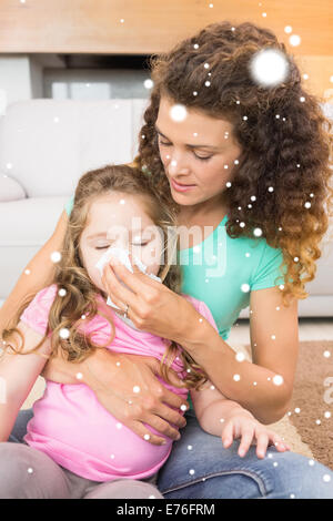 Composite image of caring mother helping her little daughter blow her nose