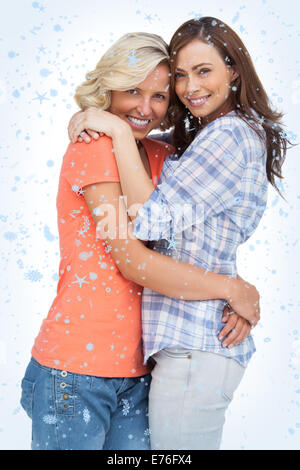 Composite image of two cute friends looking at the camera and hugging Stock Photo