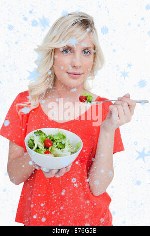 Composite image of young blonde woman eating a vegetable salad Stock Photo