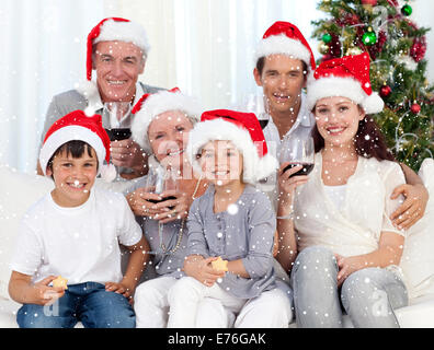 Composite image of family celebrating christmas with wine and sweets Stock Photo