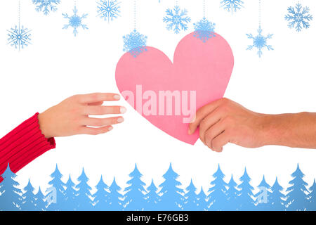 Composite image of couple passing a paper heart Stock Photo