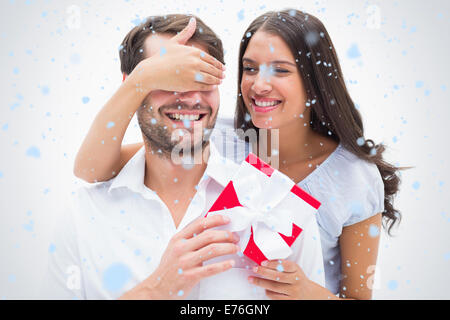 Composite image of pretty brunette surprising boyfriend with a gift Stock Photo