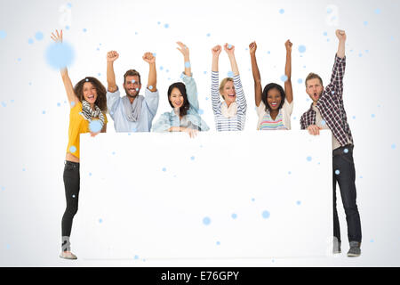 Composite image of smiling group of young friends showing large poster and cheering Stock Photo