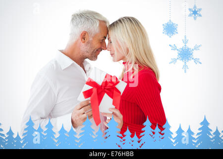 Composite image of smiling couple passing a wrapped gift Stock Photo