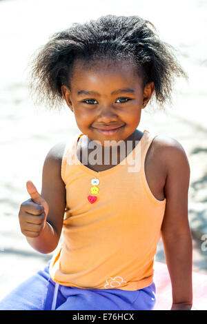 Outdoor portrait of cute African girl doing thumbs up sign. Stock Photo