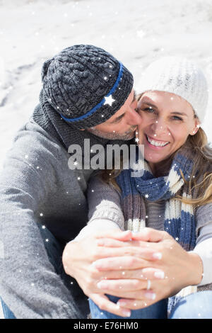 Composite image of attractive couple on the beach in warm clothing Stock Photo