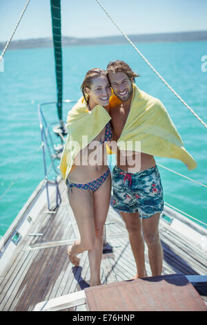 Couple sharing towel in boat on water Stock Photo