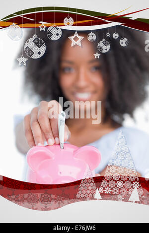 Composite image of young woman inserting notes in a piggy bank Stock Photo