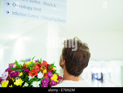 Man carrying bouquet of flowers in hospital Stock Photo