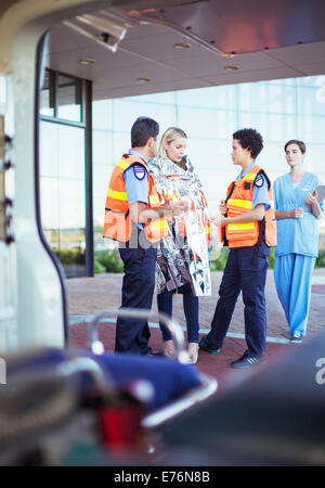 Paramedics talking to patient in hospital parking lot Stock Photo