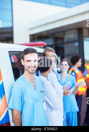 Nurse smiling by ambulance in hospital parking lot Stock Photo