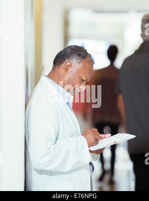 Doctor writing on medical chart in hospital Stock Photo