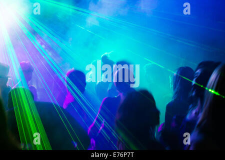 Crowd of people dancing under disco laser light. Stock Photo