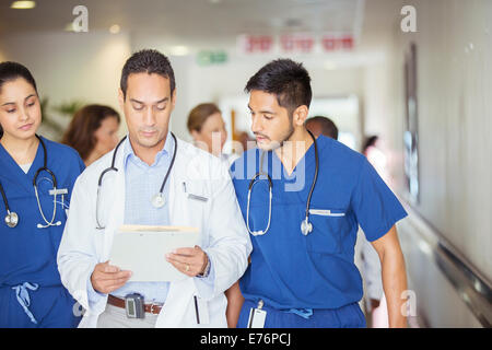 Doctor and nurses reading medical chart in hospital hallway Stock Photo
