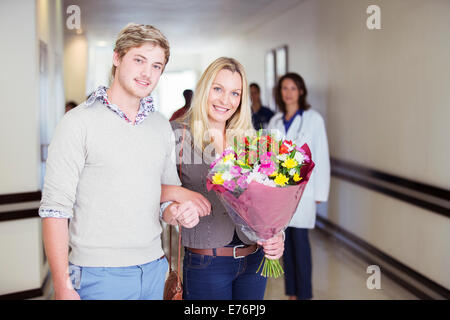 Couple carrying bouquet of flowers in hospital