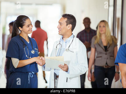 Doctor and nurse shaking hands in hospital hallway Stock Photo