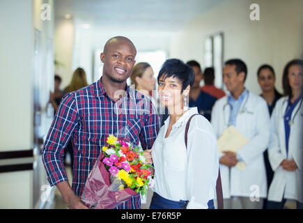 Couple carrying bouquet of flowers in hospital Stock Photo